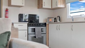A compact kitchen with a stove, oven, and toaster. There is a window with a view of the sky. - Family Caravan - Sleeps 8 - Walk to the (Prestonpans)