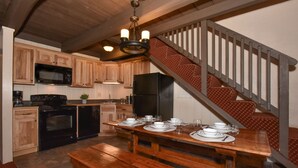 Une cuisine dotée de meubles en bois, d’un four à micro-ondes, d’une cuisinière, d’un réfrigérateur et d’une table à manger pour quatre personnes.