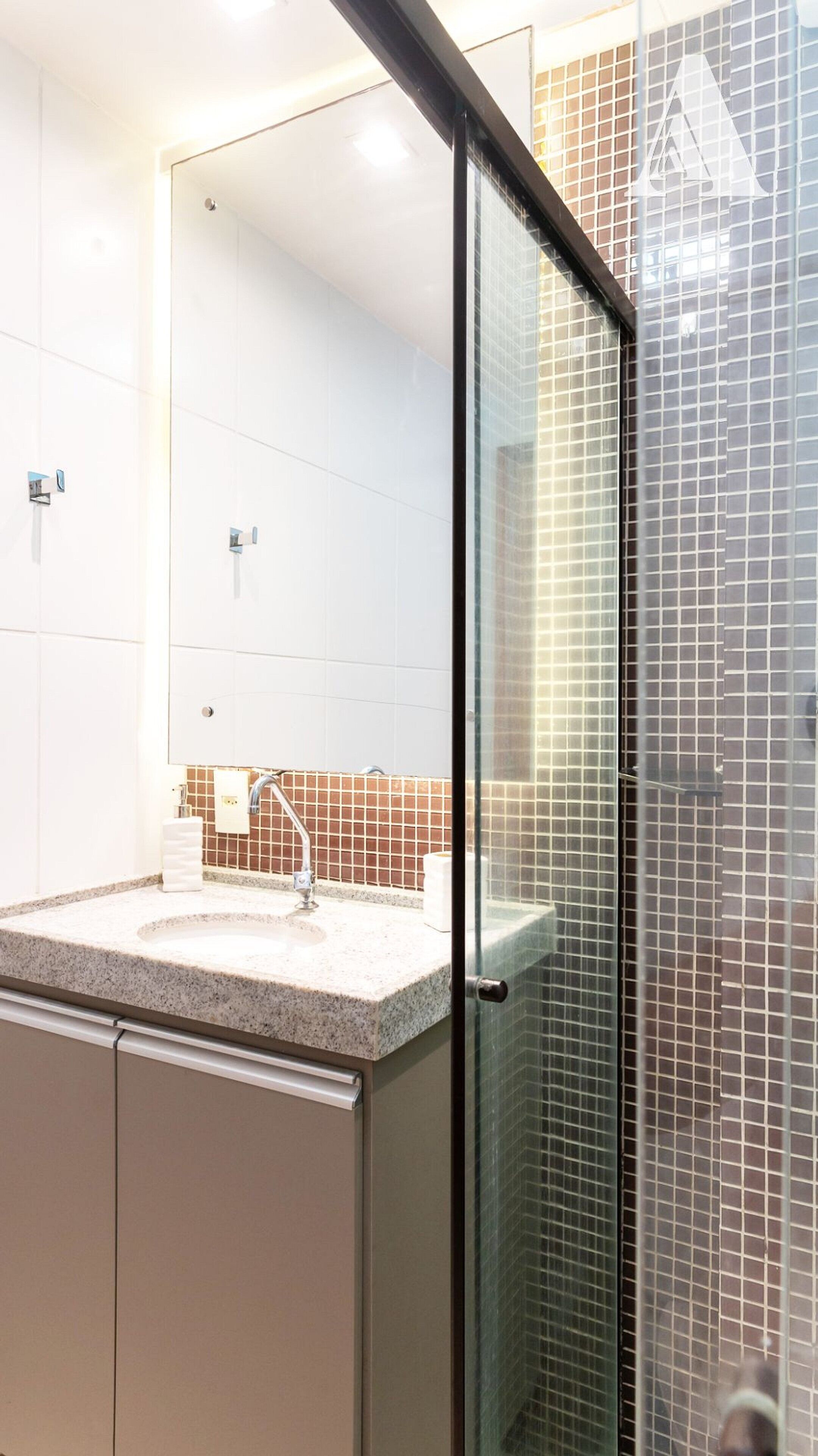 A modern bathroom with a glass shower enclosure, a sink with a mirror, and tiled walls.