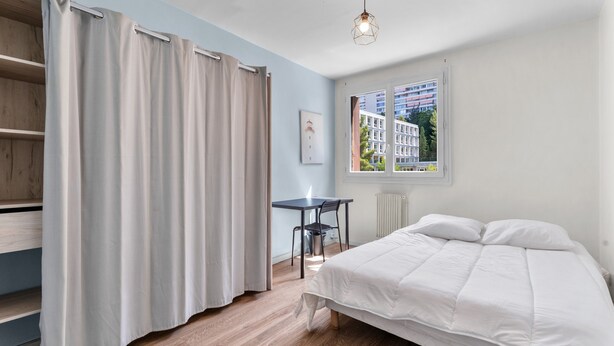 Ein Schlafzimmer mit Bett, Schreibtisch und Stuhl.