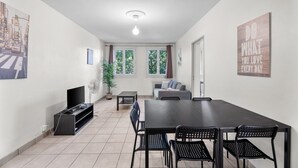 Ein modernes Wohnzimmer mit Essbereich, einem Flachbildfernseher, einem Blumentopf und einem motivierenden Poster an der Wand.