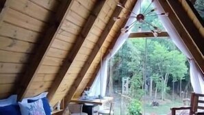 Une chambre avec un grand lit, des poutres apparentes en bois au plafond et une vue sur l’extérieur.