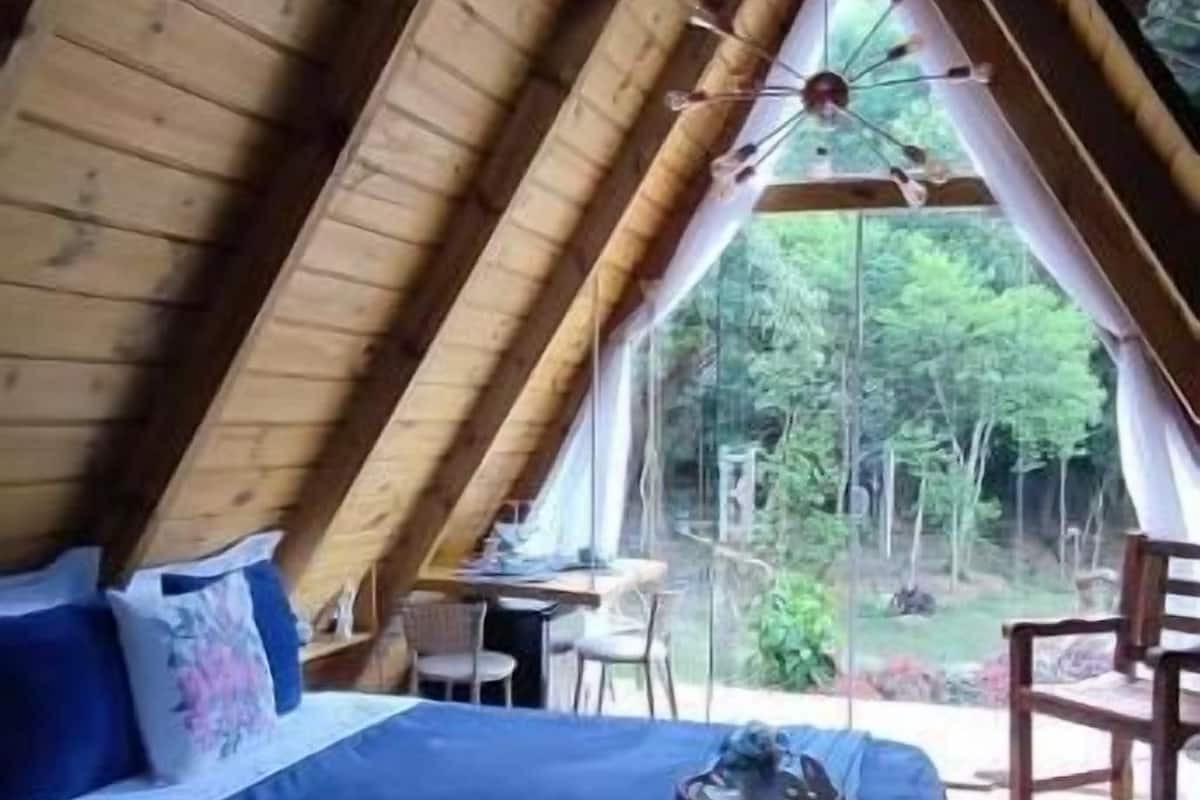 A bedroom with a large bed, wooden ceiling beams, and a view of the outdoors.