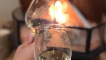 Two glasses of white wine held up in front of a fireplace.