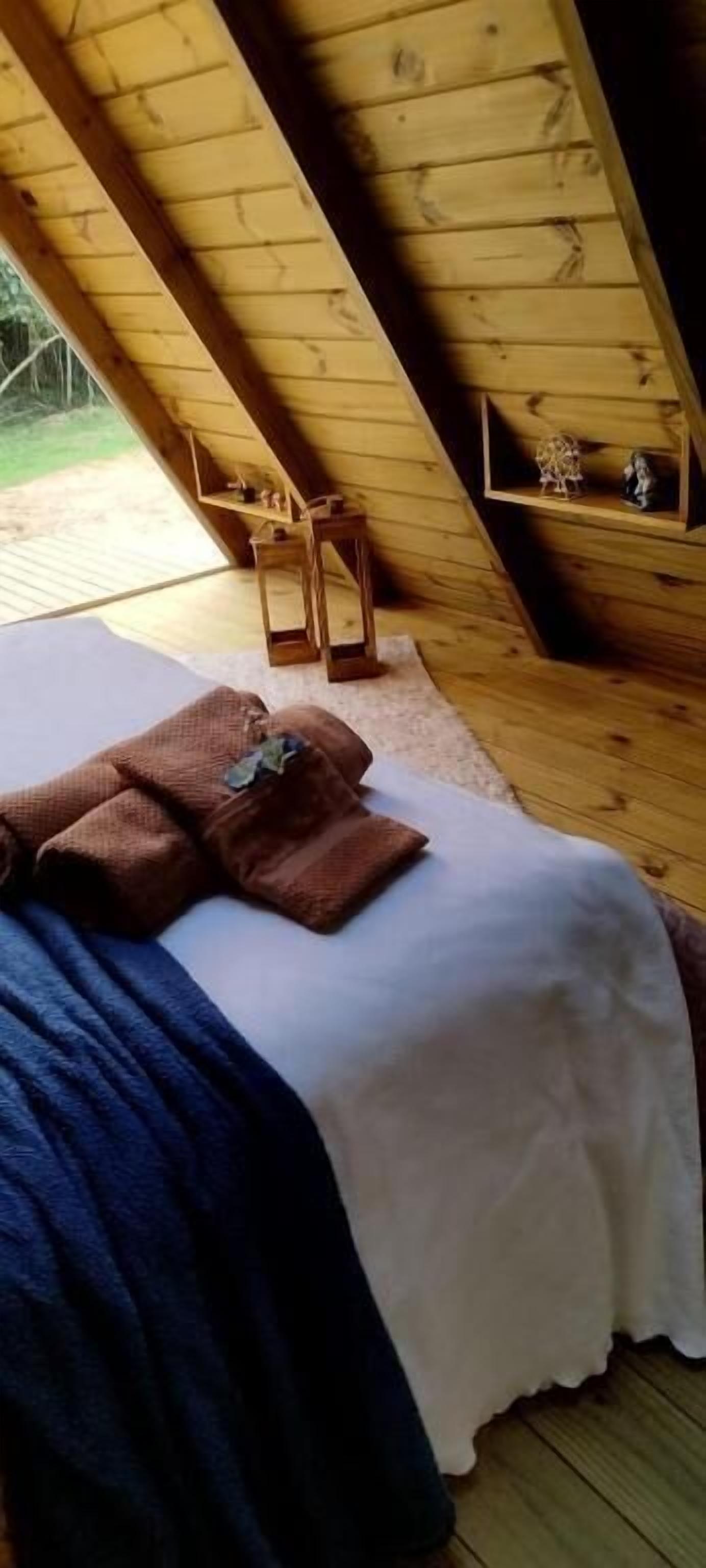 Ein Zimmer aus Holz mit einem Bett, Kissen und einem kleinen Regal mit Dekorationen.