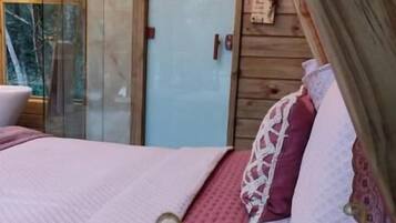 Un dormitorio acogedor con cama, techo de madera y puerta de vidrio que da al exterior.