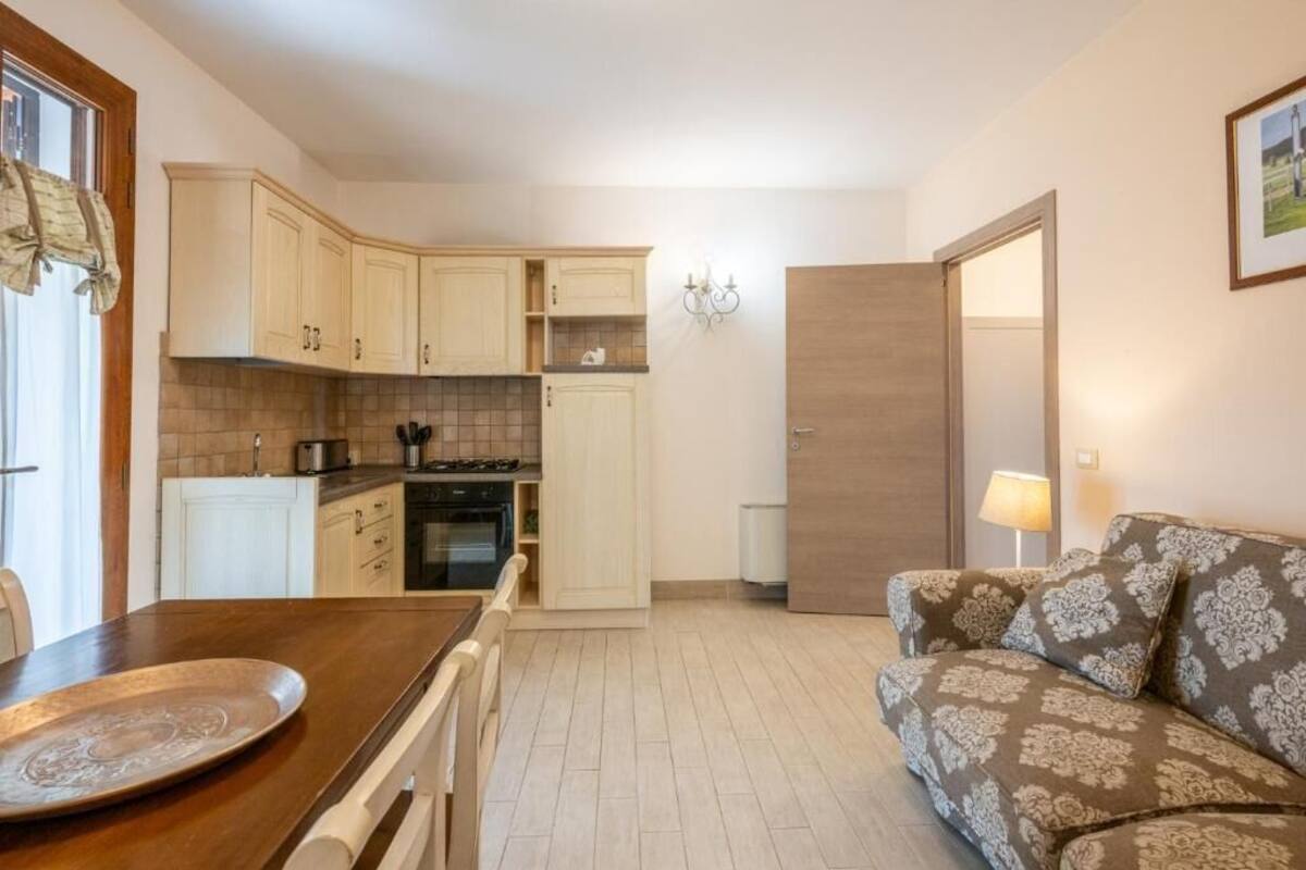 A compact kitchen with light-colored cabinets, a dining table, and a sofa.