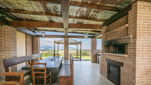 Une terrasse extérieure avec une cheminée en briques, des bancs en bois et une table.