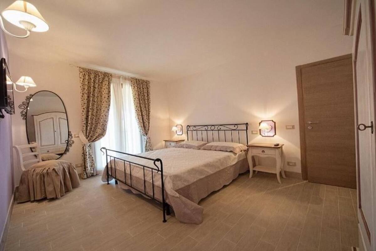 A bedroom with a bed, bedside tables, a mirror, and a door.