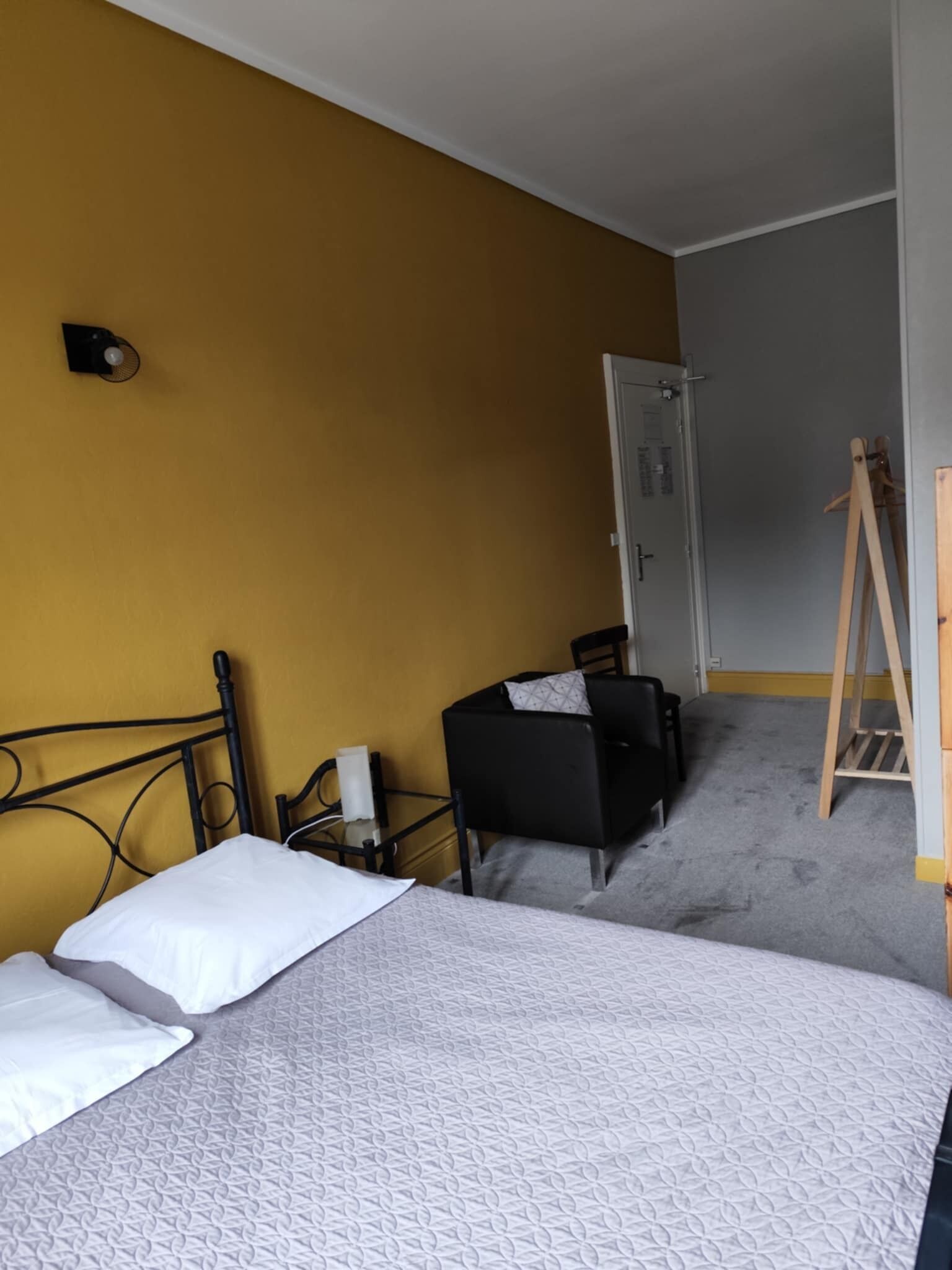 Una habitación de hotel con cama, una silla, un escritorio y un armario.