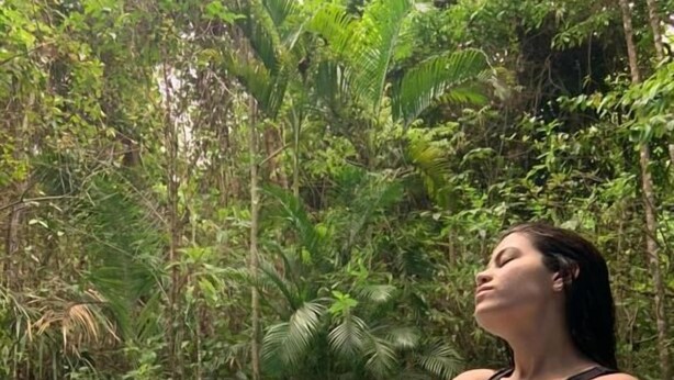 A person sitting by a pool surrounded by lush greenery. - Pousada Éden (Colinas do Sul)