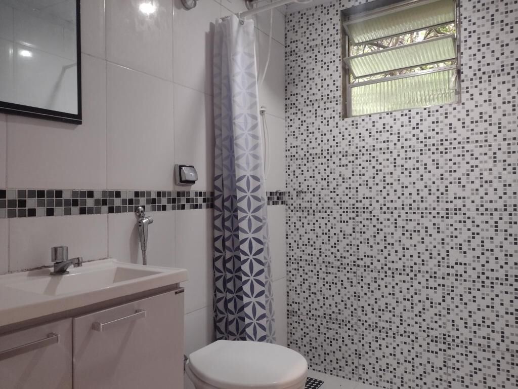 A bathroom with a white sink, a toilet, and a shower with a patterned curtain.