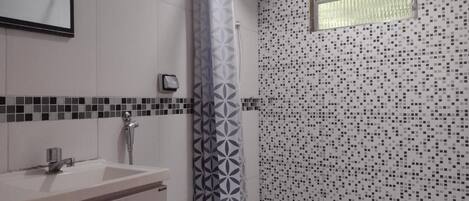 A bathroom with a white sink, a toilet, and a shower with a patterned curtain.