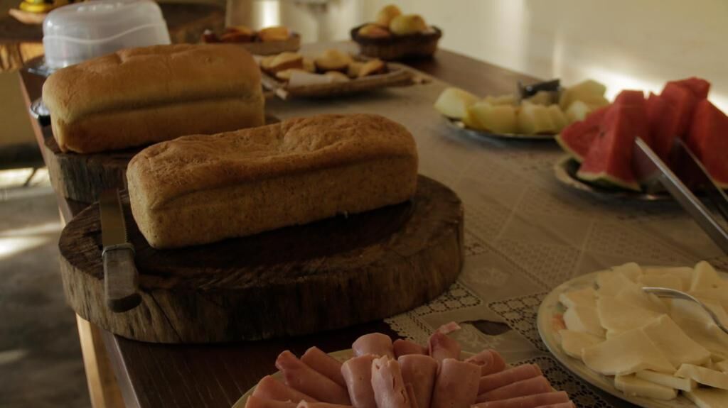 Una mesa de buffet con diversos alimentos, incluyendo pan, frutas y embutidos.