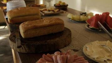 Una mesa de buffet con diversos alimentos, incluyendo pan, frutas y embutidos.