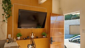 A modern bathroom with a wooden vanity, a mounted TV, and a door leading to a garage.