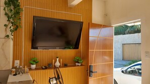 Ein modernes Badezimmer mit einem Holzbidet, einem an der Wand montierten Fernseher und einer Tür, die zu einer Garage führt.