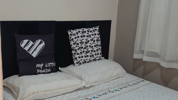 A neatly made bed with floral bedding, a black headboard, and two decorative pillows.