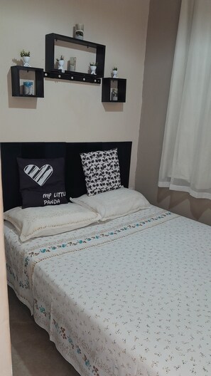 A neatly made bed with floral bedding, a black headboard, and two decorative pillows.