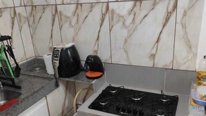 A compact kitchen with a gas stove, a coffee maker, and a kettle on the countertop.