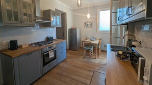 A modern kitchen with grey cabinets, a wooden countertop, a built-in oven, and a dining area with a table and chairs. - Charming retreat with terrace over Pisa's hidden gardens (Pisa)