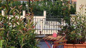 A patio area with a table and chairs under a large umbrella, surrounded by potted plants. - Charming retreat with terrace over Pisa's hidden gardens (Pisa)