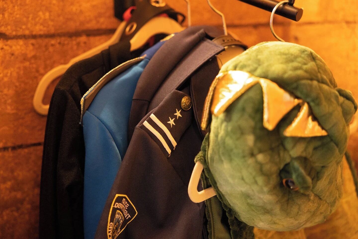 A green plush toy with a headband, hanging on a rack with other items.