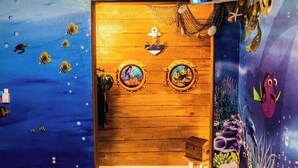 A room with a wooden door, two round windows with marine-themed artwork, and a small wooden stool. -     Family Pool Home-Near Disney, Food Festivals & Events- Book Now (Davenport)