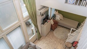 Un espace de vie compact comprenant un canapé, une petite table, une lampe et un extincteur.