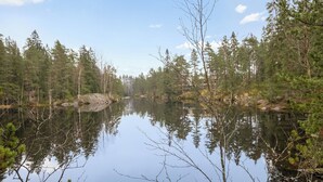 A serene lake surrounded by dense forest with clear reflections. - Korpilammenhuvilat 7a by Interhome (Espoo)