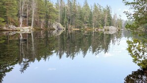 A calm lake surrounded by dense forest with clear reflections. - Korpilammenhuvilat 7a by Interhome (Espoo)