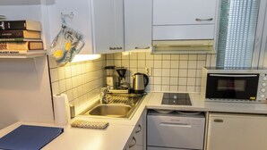 A compact kitchen with white cabinets, a built-in dishwasher, a microwave, and a coffee maker.