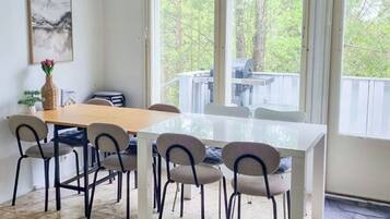 A dining area with a white table and chairs, a vase with flowers, and a painting on the wall.