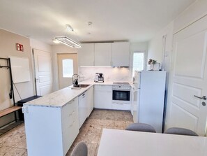 Eine kleine Küche mit weißen Schränken, einem eingebauten Backofen und einem Kühlschrank.