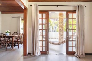 A room with a wooden dining table, chairs, and a hammock. - Authentic Beach House · 3 Bedrooms · 2 Bathrooms · Sleeps 8 (Florianópolis)