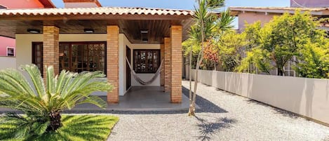 Una casa con porche cubierto, una hamaca y un camino de entrada de grava.