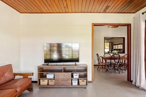 Ein Wohnzimmer mit Fernseher auf einem Holzboden, einer Couch und einem Essbereich mit Holzhöhlen und einem Tisch.