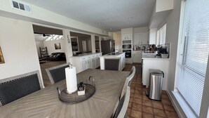 Una cocina amplia con armarios blancos, una isla central y un comedor con una mesa grande.