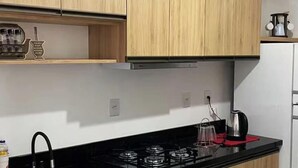 Una cocina con armarios de madera, una encimera negra, un refrigerador blanco y una estufa a gas.