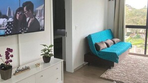 Una sala moderna con un televisor de pantalla plana, un sofá, un aparador blanco y una alfombra mullida.