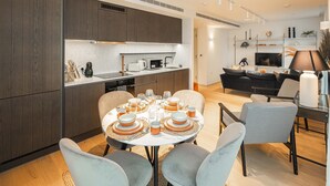 Una cucina moderna con mobili in legno scuro, un'isola centrale e un'area pranzo con tavolo rotondo imbandito per sei persone.