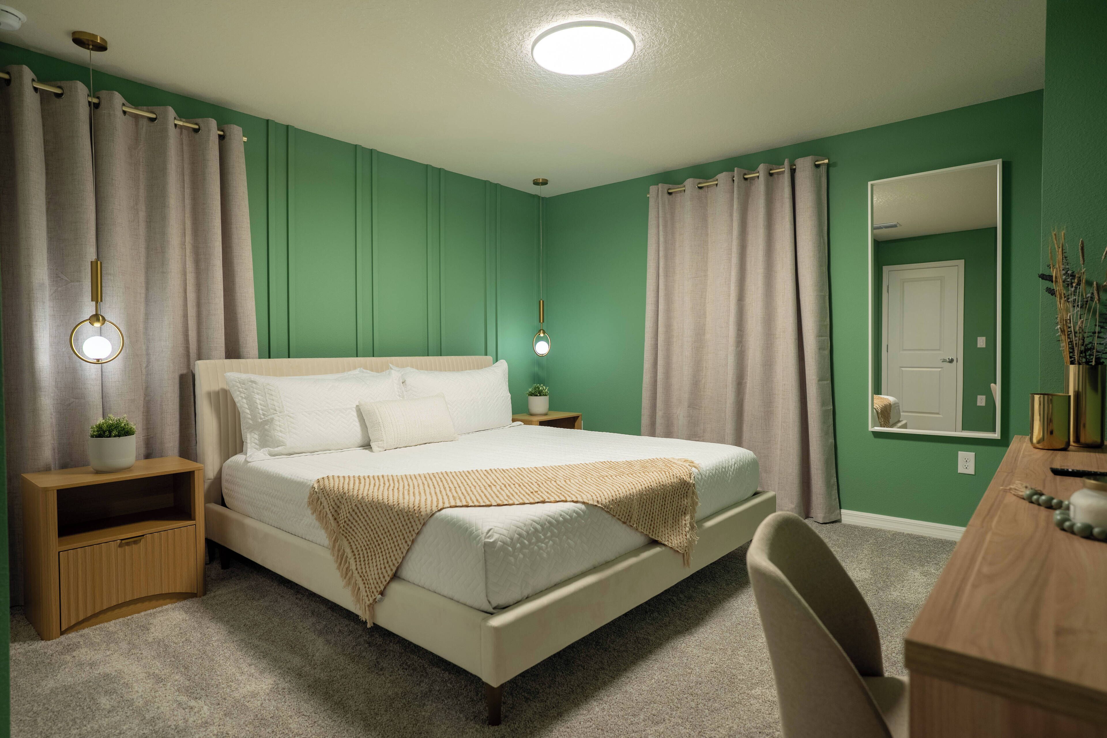 Une chambre à coucher avec un lit, des tables de chevet, un bureau et un miroir.