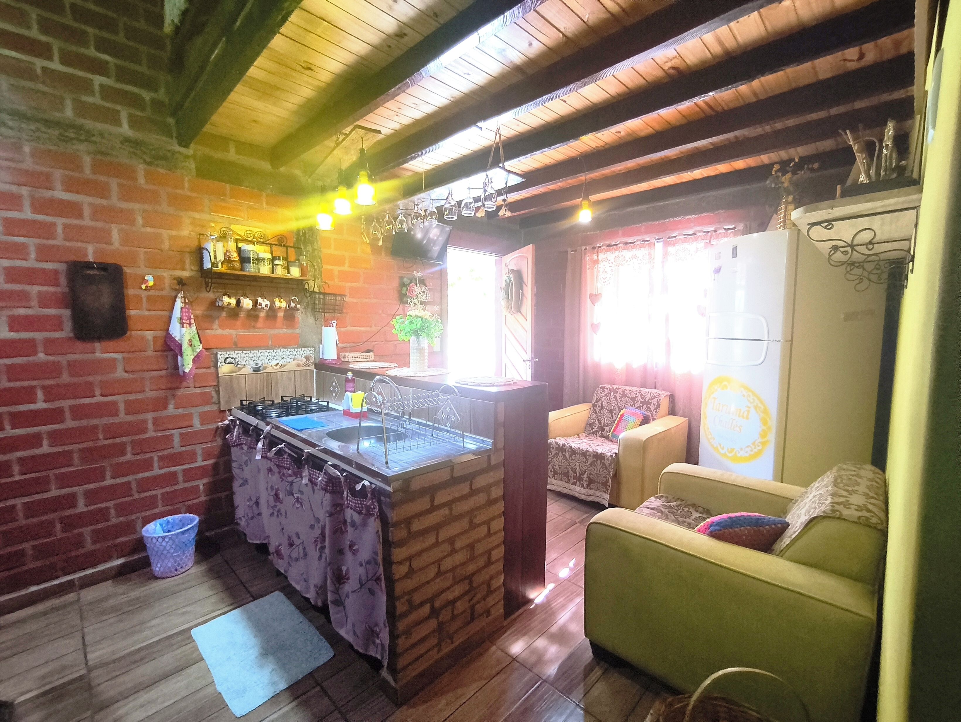 Un accogliente soggiorno con angolo cottura, soffitto in legno e un divano verde.