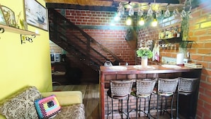 A cozy kitchen with a brick wall, wooden ceiling, and hanging light fixtures.