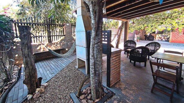 An outdoor patio area with a wooden deck, a hammock, and a seating arrangement including chairs and a table.