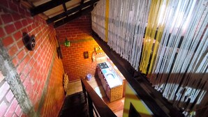 A narrow corridor with brick walls, a wooden ceiling, and a small seating area with a table and chairs.