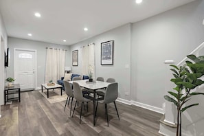 Un salon moderne avec un coin repas, des murs gris et un escalier.