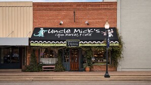 Uncle Mick's Cajun Market Cafe with a brick facade, outdoor seating, and a street lamp.