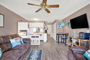 A modern living room with a brown leather couch, a coffee table, and a TV on a wooden stand. - Mermaid Memories is the perfect bay front condo.  1 bed/1 bath sleeps 4 (Tybee Island)