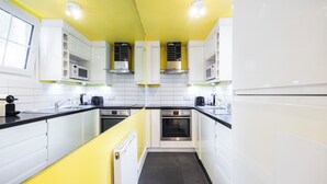 Une cuisine moderne avec des armoires blanches, des plans de travail noirs et un plafond jaune.